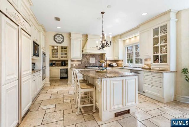 50 Claremont Rd, Fort Lee, NJ 07024 - kitchen with stone tile floors, custom range hood, stainless steel appliances, wine cooler, and decorative backsplash