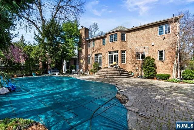 50 Claremont Rd, Fort Lee, NJ 07024 - rear view of house featuring a chimney, a patio area, a community pool, and brick siding