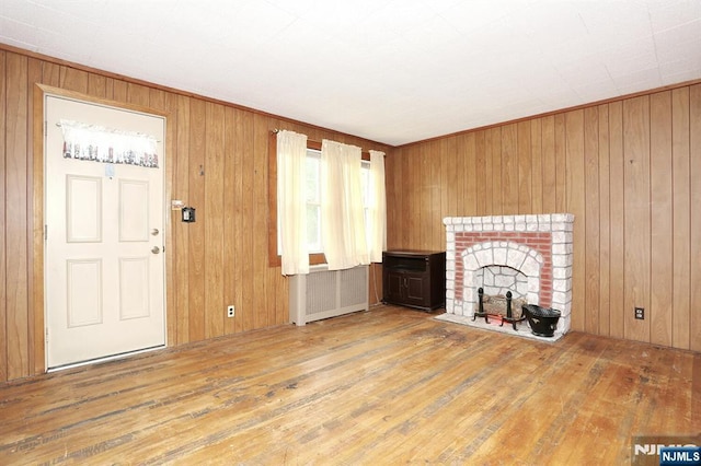16 Merritt Ave, Dumont, NJ 07628 - unfurnished living room featuring radiator, hardwood / wood-style floors, a fireplace, and wood walls