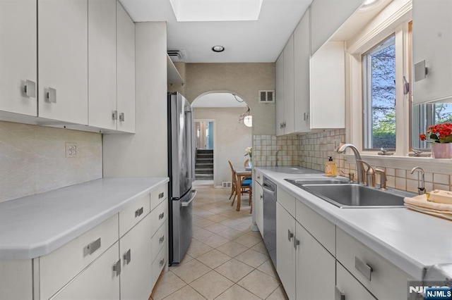 15 Strawberry Hill Rd, Hillsdale, NJ 07642 - kitchen featuring appliances with stainless steel finishes, arched walkways, a sink, light countertops, and white cabinets