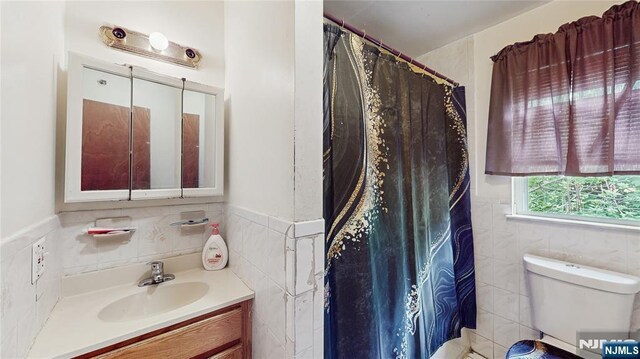 129-131 Seymour Ave, Newark, NJ 07108 - bathroom featuring tile walls, vanity, toilet, and wainscoting