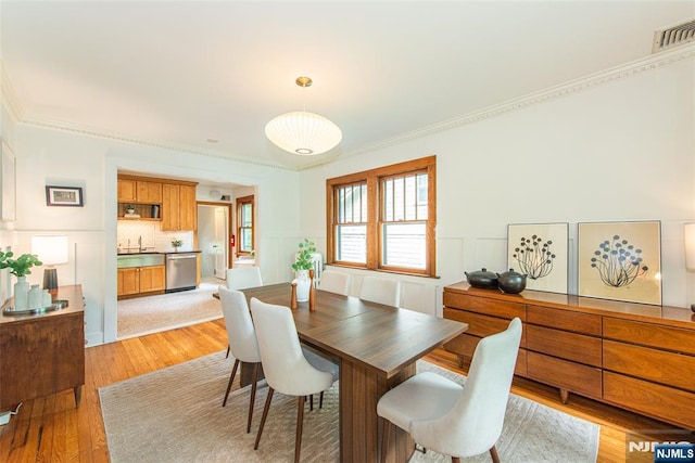 27 Nassau Rd, Montclair, NJ 07043 - dining area with light wood-type flooring, a wainscoted wall, crown molding, and a decorative wall