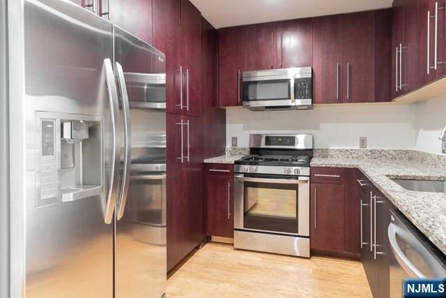 812 Hudson Park Unit 812, Edgewater, NJ 07020 - kitchen with appliances with stainless steel finishes, reddish brown cabinets, a sink, and light stone countertops