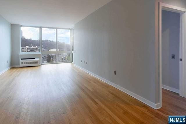 812 Hudson Park Unit 812, Edgewater, NJ 07020 - unfurnished living room featuring wood finished floors, baseboards, and a wall of windows