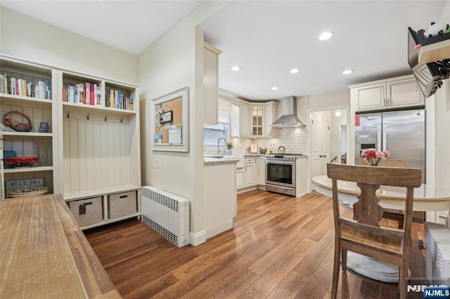 74 Oakdene Ave, Cliffside Park, NJ 07010 - kitchen with wall chimney exhaust hood, radiator heating unit, wood finished floors, stainless steel appliances, and a sink