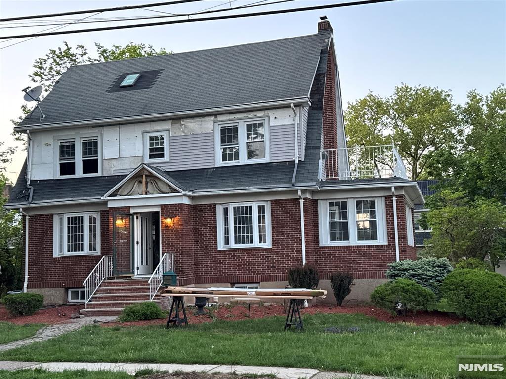 217 Grayson Pl, Teaneck, NJ 07666 - view of front of house with a chimney, brick siding, a front lawn, and a shingled roof
