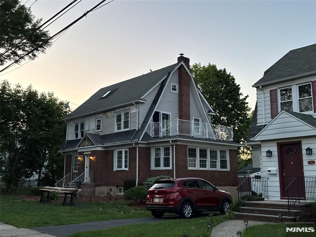 217 Grayson Pl, Teaneck, NJ 07666 - view of front of home with a chimney, a balcony, a yard, and brick siding