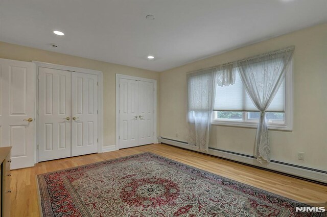 245 Forest Ave, Emerson, NJ 07630 - unfurnished bedroom with multiple closets, light wood-style flooring, a baseboard radiator, recessed lighting, and baseboards