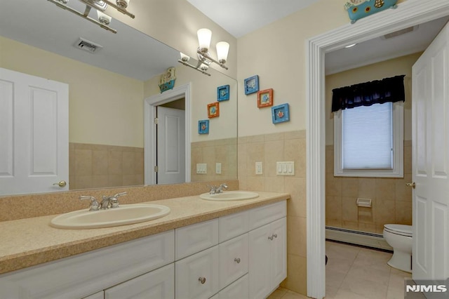 245 Forest Ave, Emerson, NJ 07630 - full bath with a baseboard radiator, tile walls, tile patterned flooring, double vanity, and toilet