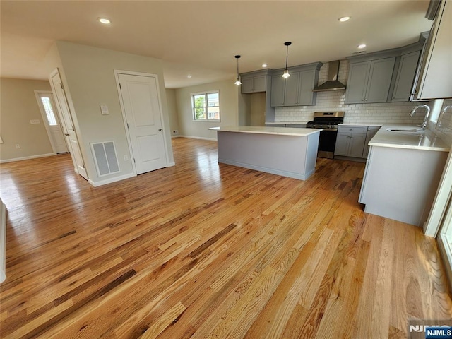 510 Anthony Ct, Lyndhurst, NJ 07071 - kitchen featuring wall chimney range hood, stainless steel range with gas cooktop, gray cabinets, a sink, and light wood-style floors