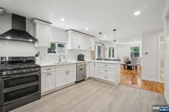 43 Lawrence Pkwy, Tenafly, NJ 07670 - kitchen featuring wall chimney range hood, appliances with stainless steel finishes, a peninsula, healthy amount of natural light, and recessed lighting