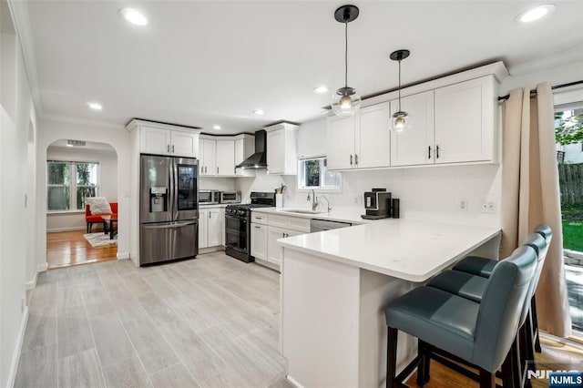 43 Lawrence Pkwy, Tenafly, NJ 07670 - kitchen featuring stainless steel appliances, wall chimney range hood, arched walkways, healthy amount of natural light, and ornamental molding