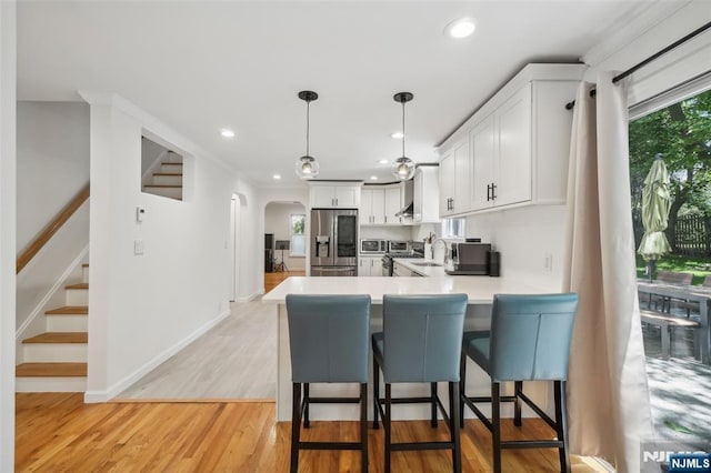 43 Lawrence Pkwy, Tenafly, NJ 07670 - kitchen with appliances with stainless steel finishes, arched walkways, a peninsula, white cabinets, and light countertops