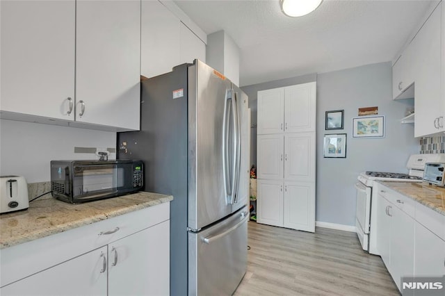 1530 Palisade Ave Unit 21M, Fort Lee, NJ 07024 - kitchen with white range with gas stovetop, freestanding refrigerator, white cabinetry, light wood finished floors, and light stone countertops