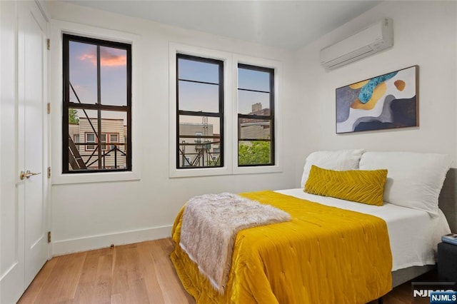 50 Grace St Unit 2R, Jersey City, NJ 07307 - bedroom with a wall unit AC, wood finished floors, and baseboards