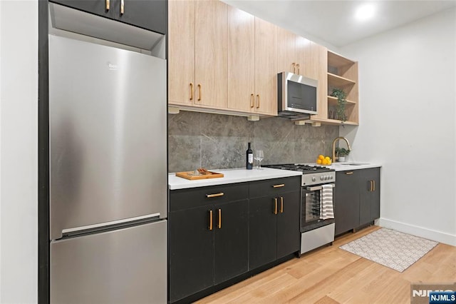 50 Grace St Unit 2R, Jersey City, NJ 07307 - kitchen featuring stainless steel appliances, a sink, light wood-style flooring, tasteful backsplash, and light countertops