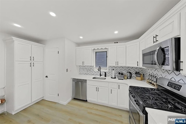 107 Elm St, West Orange, NJ 07052 - kitchen featuring appliances with stainless steel finishes, a sink, tasteful backsplash, light wood-type flooring, and white cabinetry