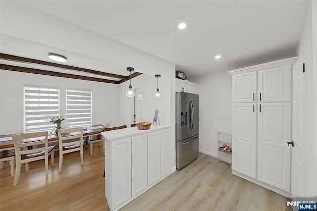 107 Elm St, West Orange, NJ 07052 - kitchen with stainless steel fridge, light wood finished floors, white cabinets, a peninsula, and hanging light fixtures