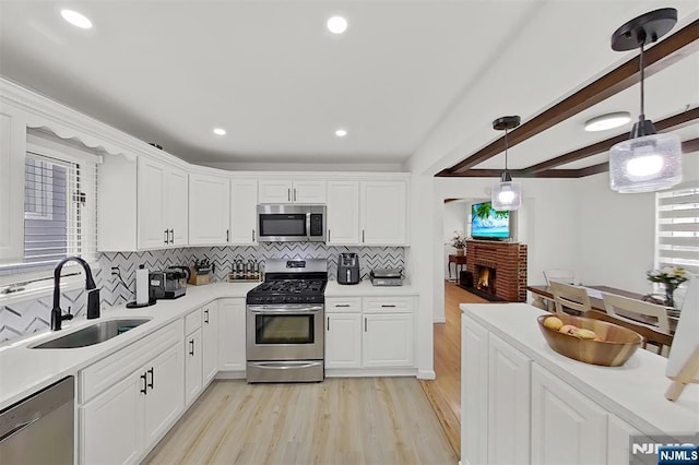 107 Elm St, West Orange, NJ 07052 - kitchen featuring appliances with stainless steel finishes, a sink, light wood-style flooring, decorative backsplash, and white cabinets