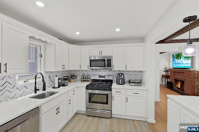 107 Elm St, West Orange, NJ 07052 - kitchen featuring appliances with stainless steel finishes, a sink, white cabinets, light wood finished floors, and light countertops