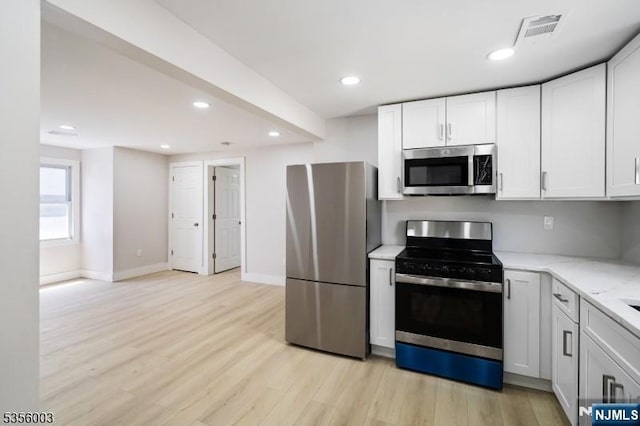 90 N Grove St, East Orange, NJ 07017 - kitchen featuring appliances with stainless steel finishes, light wood-style floors, light stone counters, recessed lighting, and white cabinetry