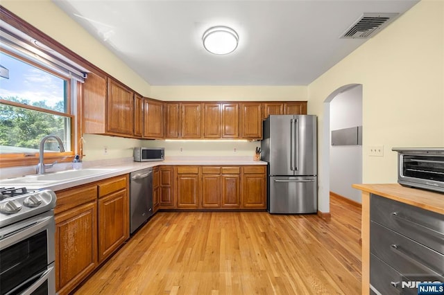 67 Short Pl, Cresskill, NJ 07626 - kitchen with stainless steel appliances, a sink, brown cabinets, and arched walkways