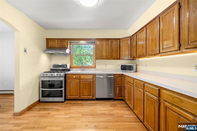 67 Short Pl, Cresskill, NJ 07626 - kitchen with stainless steel appliances, a baseboard heating unit, arched walkways, a sink, and under cabinet range hood