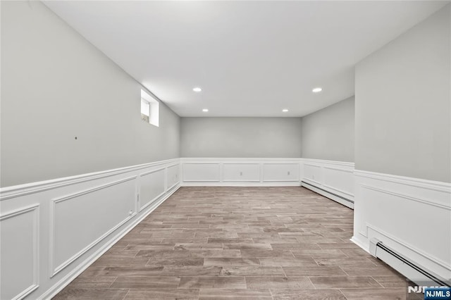 15 Kossuth St, Wallington, NJ 07057 - empty room featuring baseboard heating, recessed lighting, wood finished floors, a wainscoted wall, and a decorative wall