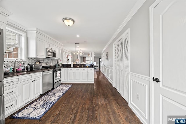 15 Kossuth St, Wallington, NJ 07057 - kitchen featuring appliances with stainless steel finishes, a peninsula, a sink, plenty of natural light, and ornamental molding