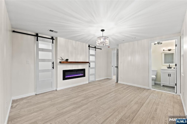 428 Elm Ave, River Edge, NJ 07661 - unfurnished living room with a barn door, light wood-style floors, a chandelier, and baseboards