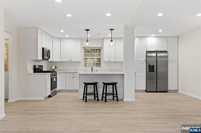 428 Elm Ave, River Edge, NJ 07661 - kitchen with stainless steel appliances, baseboards, a breakfast bar area, light wood finished floors, and recessed lighting