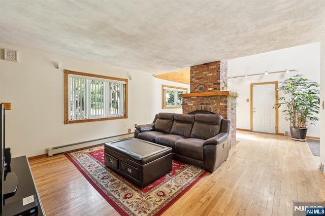 650 5th Ave, River Edge, NJ 07661 - living room featuring a baseboard heating unit, wood-type flooring, track lighting, baseboards, and a textured ceiling