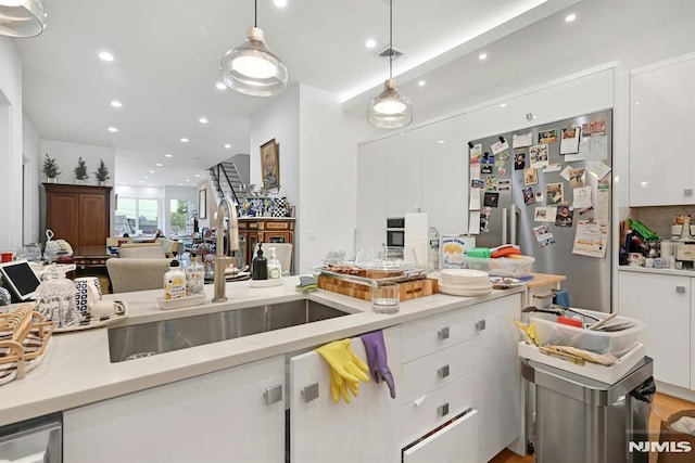 712 Undercliff Ave, Edgewater, NJ 07020 - kitchen with a sink, stainless steel fridge, white cabinetry, light countertops, and recessed lighting