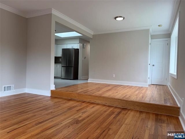 41 Woods Ave, Bergenfield, NJ 07621 - spare room featuring light wood-style flooring, baseboards, a skylight, and crown molding