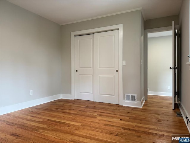 41 Woods Ave, Bergenfield, NJ 07621 - unfurnished bedroom featuring light wood-type flooring, a closet, baseboards, and crown molding