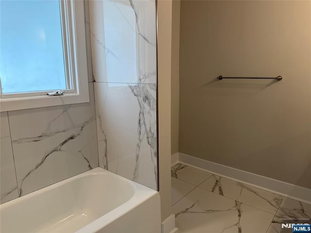 41 Woods Ave, Bergenfield, NJ 07621 - bathroom with marble look tile flooring, a tub, and baseboards