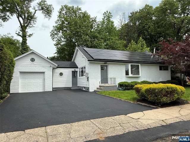 41 Woods Ave, Bergenfield, NJ 07621 - ranch-style home featuring a garage, brick siding, roof mounted solar panels, asphalt driveway, and a shingled roof