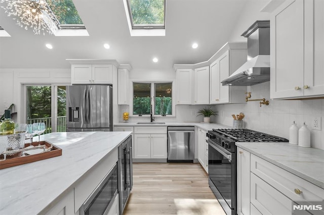 104 Myrtle Ave, Ramsey, NJ 07446 - kitchen with stainless steel appliances, wall chimney range hood, a skylight, tasteful backsplash, and white cabinets