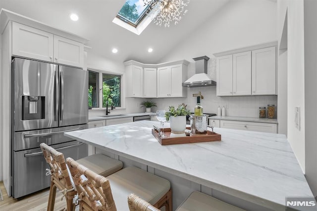104 Myrtle Ave, Ramsey, NJ 07446 - kitchen with stainless steel refrigerator with ice dispenser, wall chimney exhaust hood, a skylight, decorative backsplash, and white cabinetry