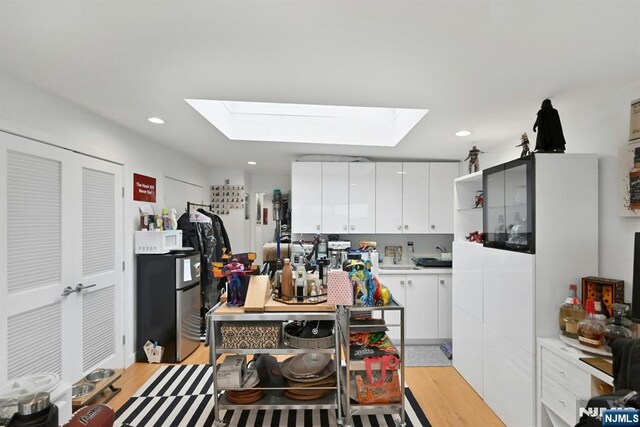 716 Undercliff Ave, Edgewater, NJ 07020 - kitchen with a skylight, white cabinetry, light countertops, recessed lighting, and light wood-type flooring