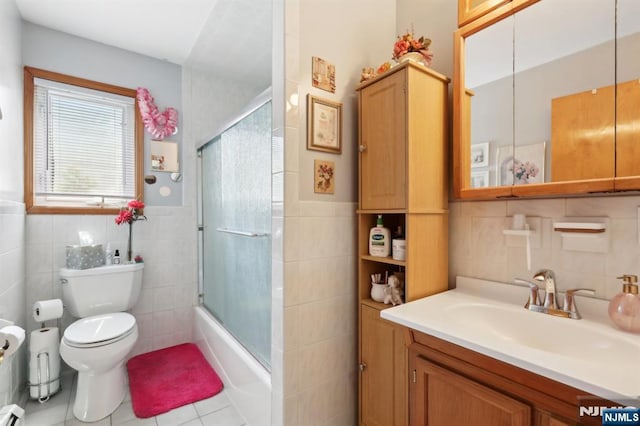 300 Wilson Ave, Lyndhurst, NJ 07071 - bathroom with tile walls, toilet, vanity, tile patterned flooring, and combined bath / shower with glass door