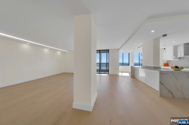 200 Winston Unit 2912, Cliffside Park, NJ 07010 - kitchen with light wood-style floors, white cabinetry, wall chimney range hood, modern cabinets, and floor to ceiling windows