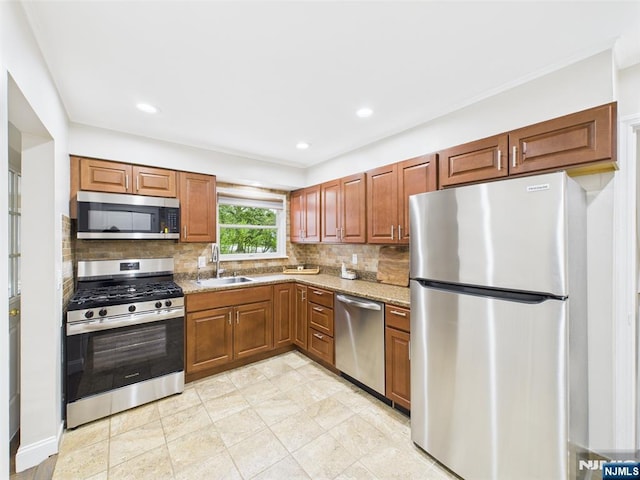 440 Albin Ct, Ridgewood, NJ 07450 - kitchen featuring appliances with stainless steel finishes, a sink, backsplash, light stone countertops, and brown cabinets