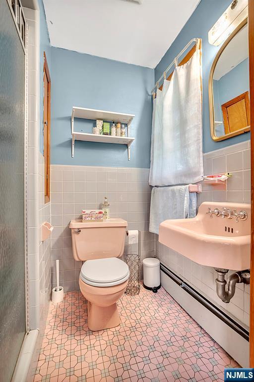 42 Cecilia Dr, Wayne, NJ 07470 - full bath with tile walls, a baseboard heating unit, toilet, a stall shower, and a sink