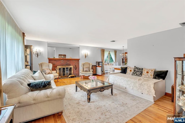 42 Cecilia Dr, Wayne, NJ 07470 - living room featuring light wood finished floors, a chandelier, and a brick fireplace