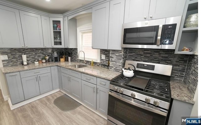 516 Beardsley Ave, Bloomfield, NJ 07003 - kitchen featuring stainless steel appliances, a sink, light wood finished floors, backsplash, and glass insert cabinets