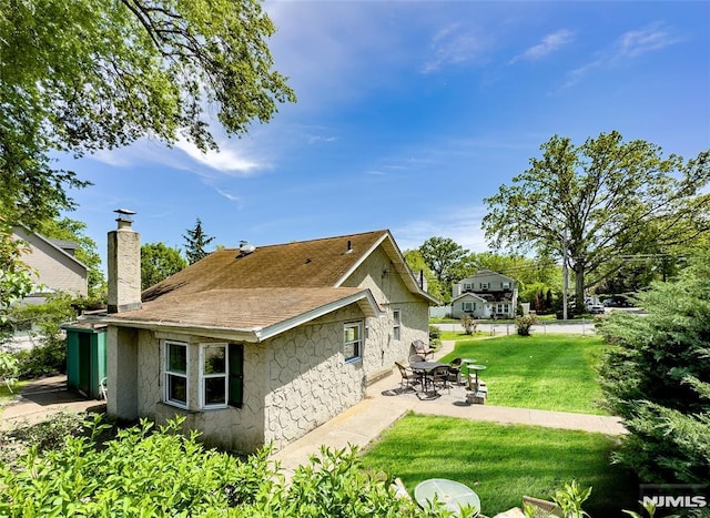 51 Minnehaha Blvd, Par-Troy Hills Twp, NJ 07034 - back of house with a patio, a chimney, a lawn, roof with shingles, and stone siding