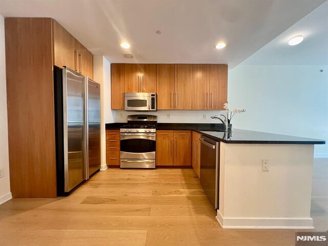 800 12th St Unit 207, Palisades Park, NJ 07650 - kitchen featuring stainless steel appliances, a sink, dark countertops, a peninsula, and brown cabinetry