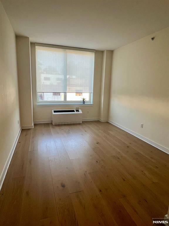 800 12th St Unit 207, Palisades Park, NJ 07650 - empty room with wood finished floors, healthy amount of natural light, a wall mounted air conditioner, and baseboards