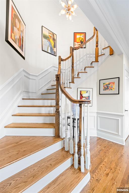 6 Lauren Pond Ct, Demarest, NJ 07627 - stairs with a decorative wall, a chandelier, wood finished floors, and a wainscoted wall